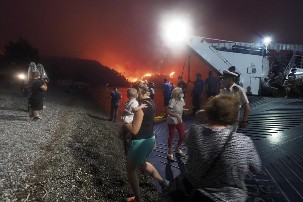 People embark a ferry during an evacuation from Kochyli beach as wildfire approaches near Limni village on the island of Evia, about 160 kilometers (100 miles) north of Athens, Greece, Friday, 6 August 2021. Thousands of people fled wildfires burning out of control in Greece and Turkey on Friday, including a major blaze just north of the Greek capital of Athens that claimed one life, as a protracted heat wave left forests tinder-dry and flames threatened populated areas and electricity installations. Photo: Thodoris Nikolaou / AP Photo