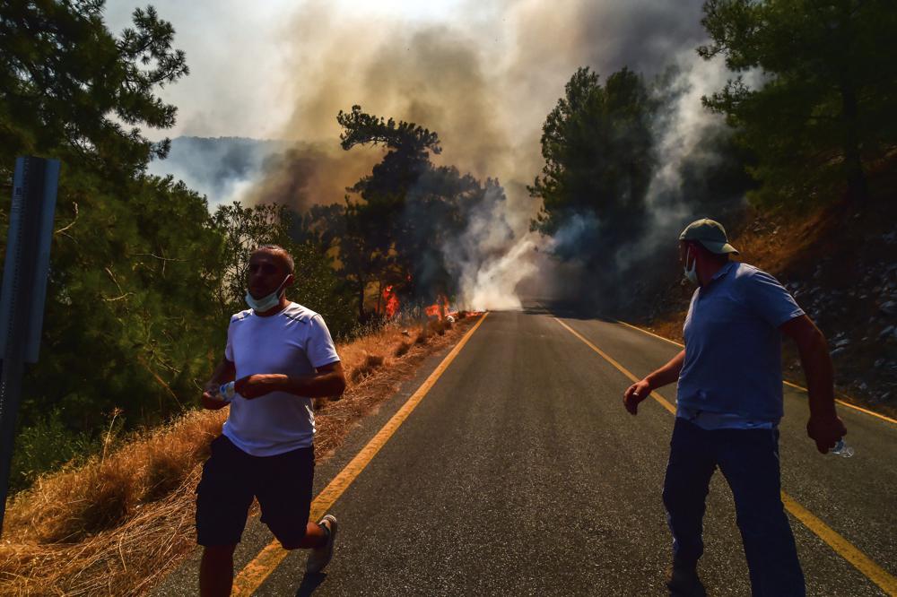 People run away as the wildfires engulf an area near the seashore, forcing people to be evacuated by boats, in Bodrum, Mugla, Turkey, Sunday, 1 August 2021. Wildfires in the Turkish holiday destinations of Antalya and Mugla are still raging as firefighters worked to battle the blazes for a fifth day. Authorities warned tourists and residents to keep evacuating Turunc, a town in the seaside resort of Marmaris, and navy ships waited in the sea there to see if a bigger evacuation was needed. Photo: Ismail Coskun / IHA / AP