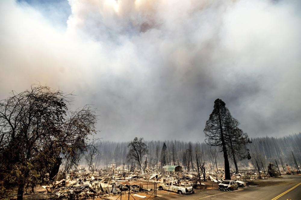 Smoke rises behind cars, homes, and forest destroyed by the Dixie Fire in central Greenville on Thursday, 5 August 2021, in Plumas County, California. Photo: Noah Berger / AP Photo