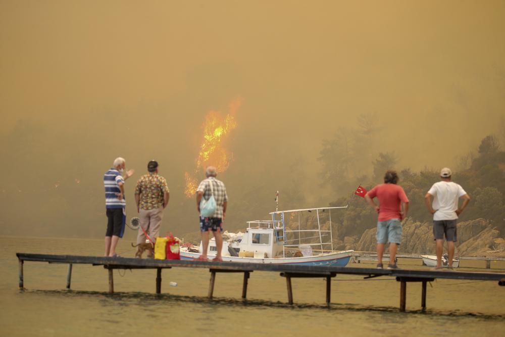 Tourists wait to be evacuated from smoke-engulfed Mazi area as wildfires rolled down the hill toward the seashore, in Bodrum, Mugla, Turkey, Sunday, 1 August 2021. More than 100 wildfires have been brought under control in Turkey, according to officials. The forestry minister tweeted that five fires are continuing in the tourist destinations of Antalya and Mugla. Photo: Emre Tazegul / AP Photo