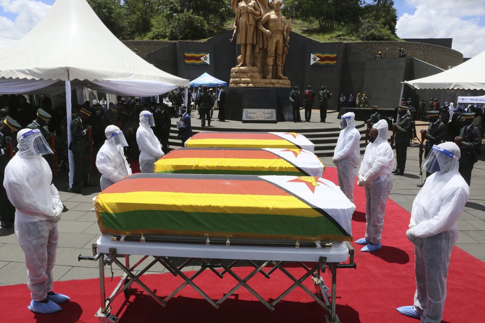 Pallbearers stand next to coffins of three top government officials at their burial at the National Heroes acre in Harare, Wednesday, 27 January 2021. Zimbabwe on Wednesday buried three top officials who succumbed to COVID-19, in a single ceremony at a shrine reserved almost exclusively for the ruling elite as a virulent second wave of the coronavirus took a devastating toll on the country. Photo: Tsvangirayi Mukwazhi / AP Photo