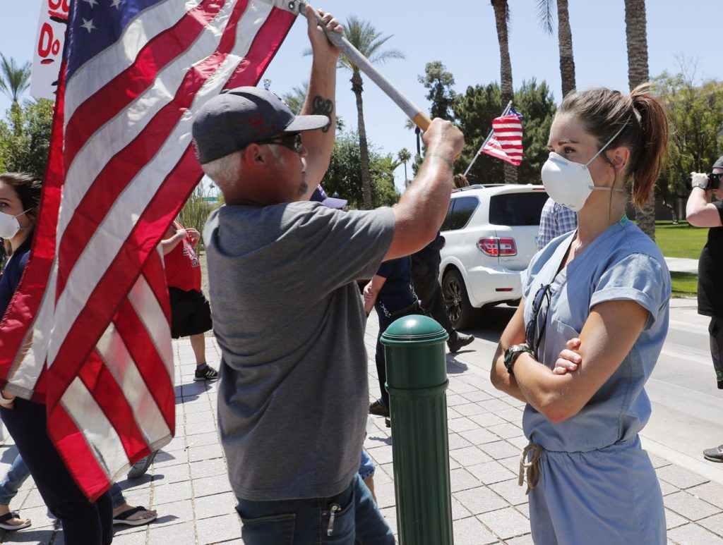 Banner University Medical Center ICU nurse Lauren Leander stands in counter-protest as people march toward the Arizona State Capitol in protest of Gov. Doug Ducey's stay-at-home order to combat the coronavirus, 20 April 2020. Photo: Michael Chow / The Arizona Republic