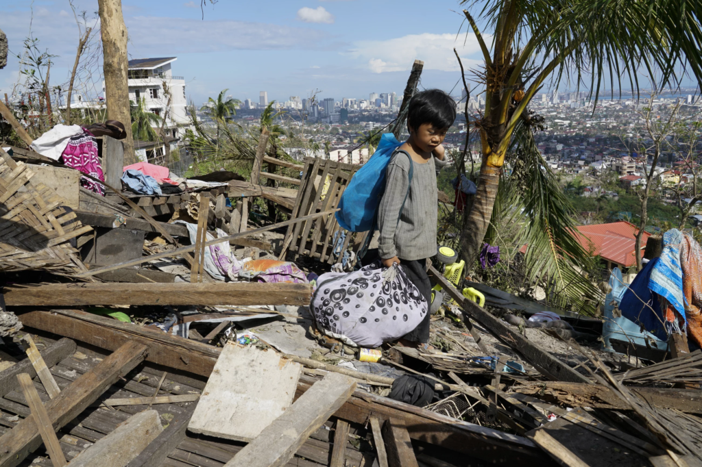 A child named Romel Lo-ang recovers personal belongings on 19 December 2021 from the remains of his family’s home destroyed by Typhoon Rai in Cebu province, central Philippines, on the 16 December 2021. Photo: Jay Labra / AP