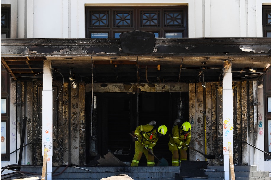 Firefighters work near the charred entrance to Old Parliament House in Canberra, Australia, on 30 December 2021. A group called People’s Treaty had gathered at Old Parliament House in recent days, organizing its activities in a Telegram channel seen by The Washington Post. The group’s website references the “deep state” and says it believes in dissolving all forms of government, and that it opposes mandatory vaccinations and coronavirus restrictions. Photo: Lukas Coch / EPA-EFE / Shutterstock