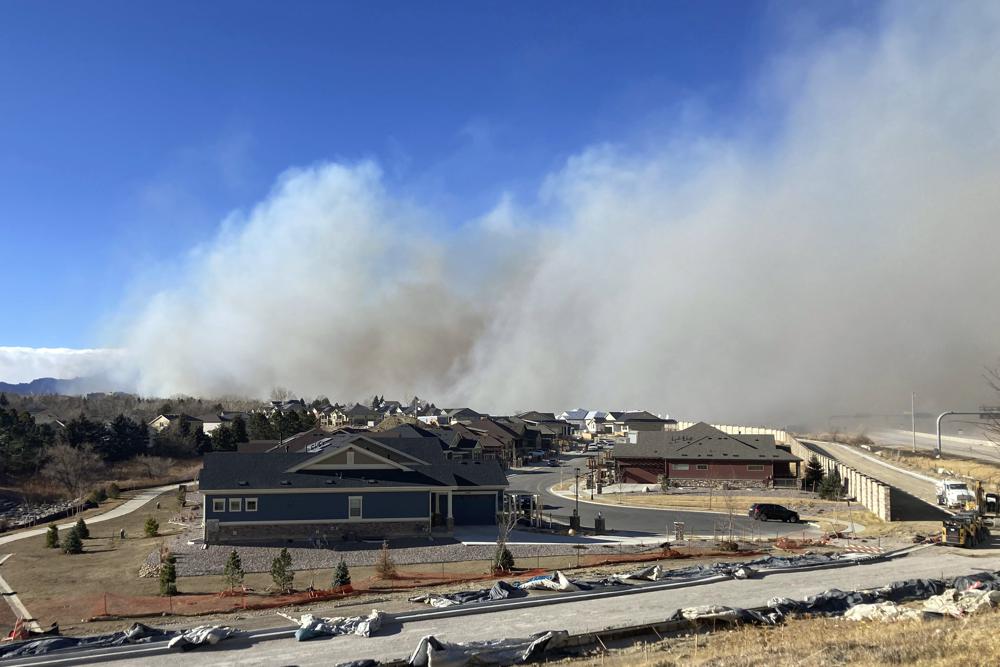 Smoke from a wildfire rises behind a neighborhood in Superior, Colorado on 30 December 2021. All 13,000 residents of the northern Colorado town were ordered to evacuate because of a wildfire driven by strong winds. Photo: David Zelio / AP Photo