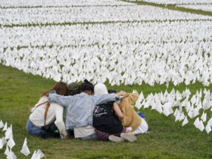 In September 2021, visitors sit amid white flags that were part of artist Suzanne Brennan Firstenberg’s In America: Remember, a temporary art installation that commemorated Americans who have died of COVID-19, on the National Mall in Washington, D.C. Photo: Patrick Semansky / AP