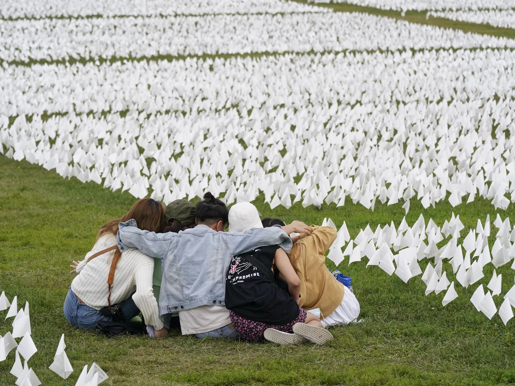 In September 2021, visitors sit amid white flags that were part of artist Suzanne Brennan Firstenberg’s “In America: Remember”, a temporary art installation that commemorated Americans who have died of COVID-19, on the National Mall in Washington, D.C. Photo: Patrick Semansky / AP