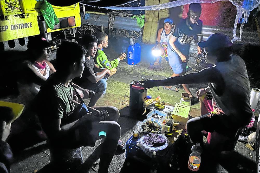 Truck drivers bound for Metro Manila celebrate Christmas Eve 2021 under a makeshift tent along the national highway in Surigao City as the Lipata port remained closed due to heavy damage from Super Typhoon Rai (Odette). Photo: Erwin M. Mascariñas / Philippine Daily Inquirer