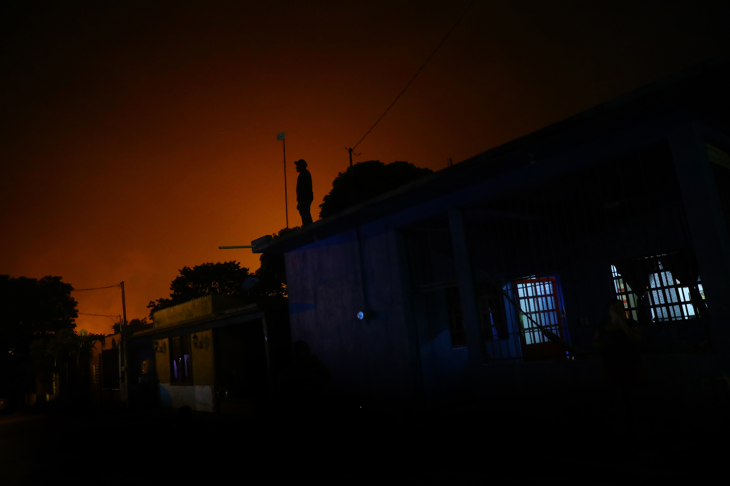 A man stands on the roof of a house in Colonia El Carmen as a red glare emanates from flares dotted around the Cactus gas processing center, run by state oil company Pemex, in Reforma municipality in Chiapas, Mexico. Photo: Edgard Garrido / REUTERS
