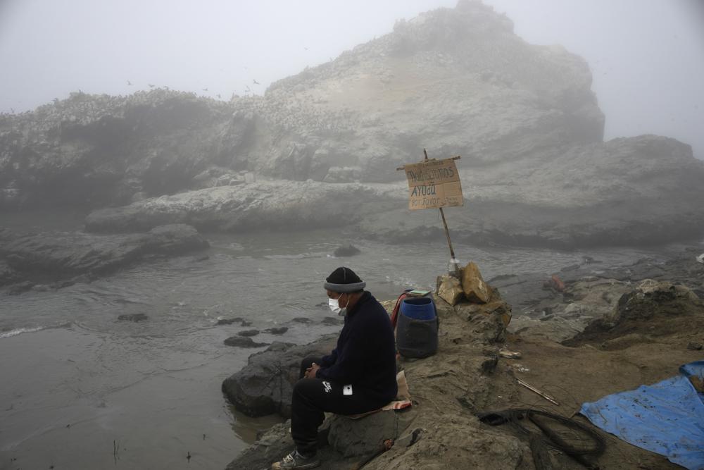 Fisherman Walter de la Cruz sits on the shore of the oil-stained Cavero Beach, unable to fish after a spill in the Ventanilla district of Callao, Peru, 21 January 2022. De la Cruz, 60, is one of more than 2,500 fishermen whose livelihoods have been cast into doubt as a result of a large crude-oil spill by the Spanish-owned Repsol oil refinery on 15 January 2022. Photo: Martin Mejia / AP Photo