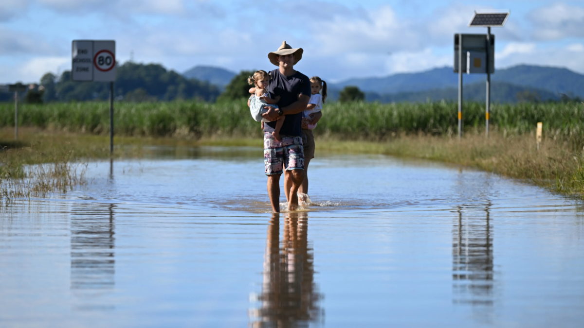 John Lawrence and Payton Campbell (unseen at rear) with their children Harlow and Aria inspect a flooded road near their home on 2 March 2022 in Dungay, Australia. Several northern New South Wales towns were forced to evacuate as Australia faced unprecedented storms and the worst flooding in a decade. Photo: Dan Peled / Getty Images