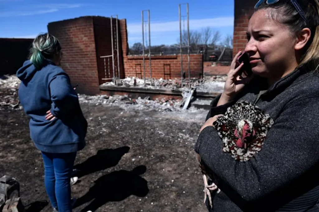 Priscilla Maynard holds a chicken while taking on the phone in front of her incinerated home on Friday, 18 March 2022 near Carbon, Texas in Eastland County. Photo: Ronald W. Erdrich / The Abilene Reporter-News / AP