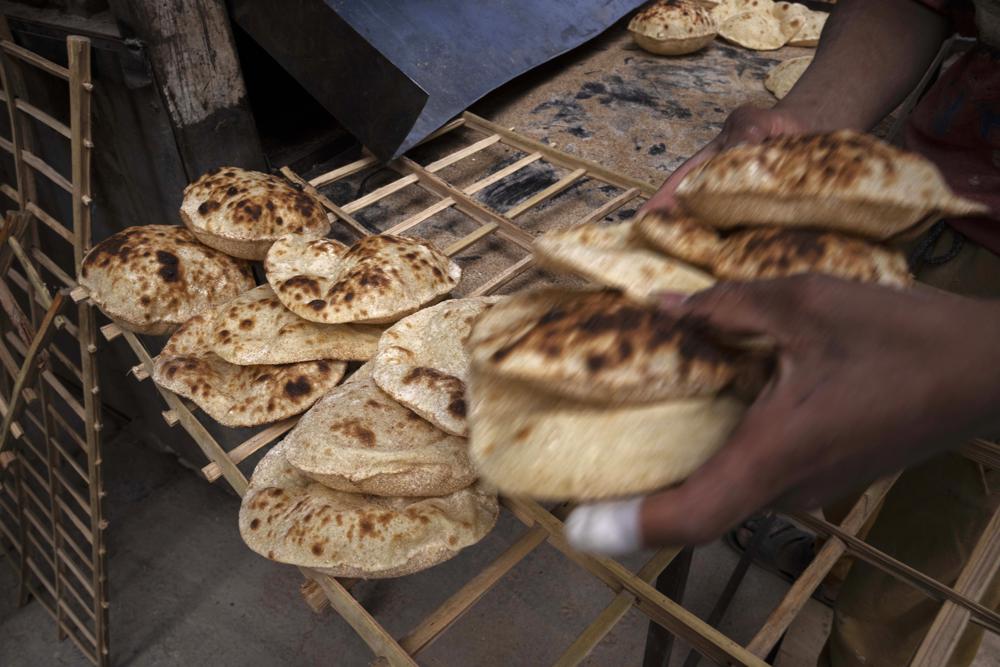 A worker collects Egyptian traditional “baladi” flatbread, at a bakery, in el-Sharabia, Shubra district, Cairo, Egypt, on Wednesday, 2 March 2022. Ukraine’s government banned the export of wheat, oats, and other food staples on Wednesday, 9 March 2022 as authorities try to make sure they can feed people while Russia’s invasion intensifies. Photo: Nariman El-Mofty / AP Photo
