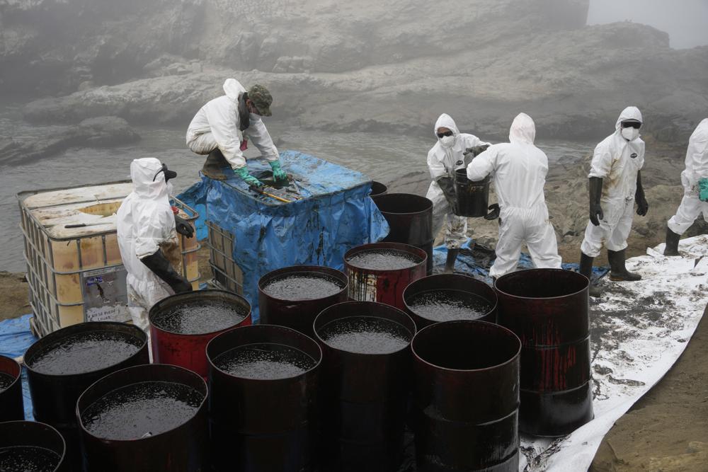 Workers remove oil waste from Cavero Beach in the Ventanilla district of Callao, Peru, 21 January 2022, following the Repsol oil spill caused by a tsunami from the eruption of an underwater volcano near Tonga. Peru has characterized the 15 January 2022 spill as its “worst ecological disaster”. Photo: Martin Mejia / AP Photo