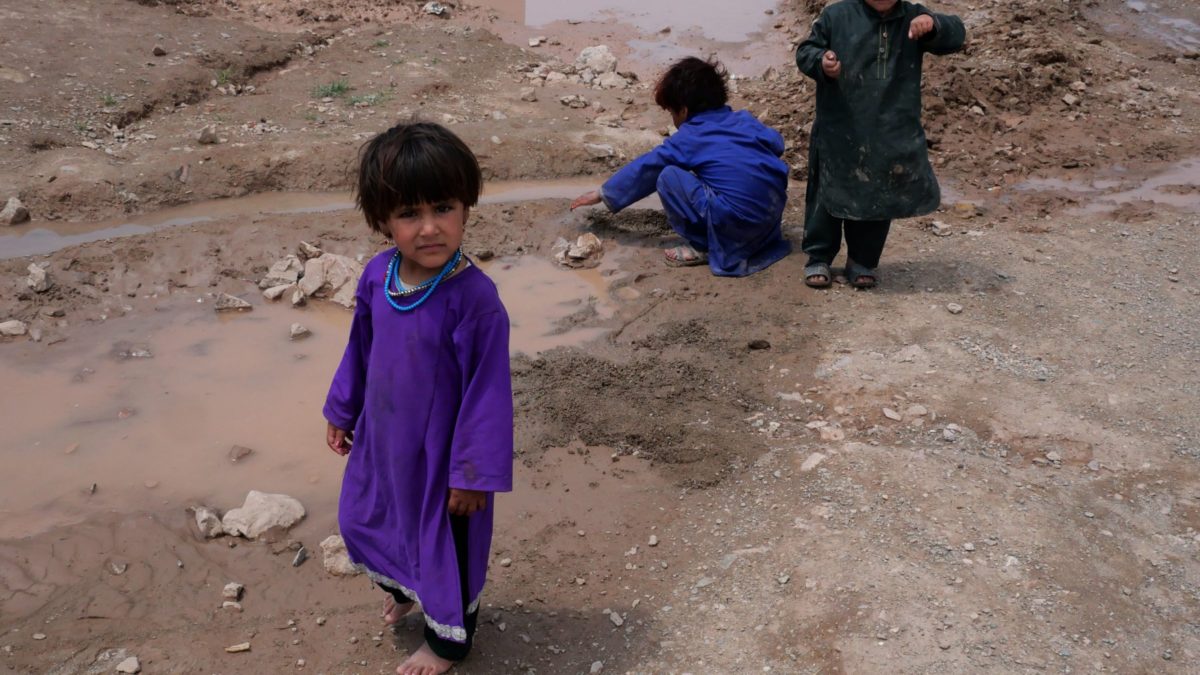 Afghan children play in the mud at an unofficial camp for internally displaced people in Herat, Afghanistan, May 2021. Photo: Charlie Faulkner
