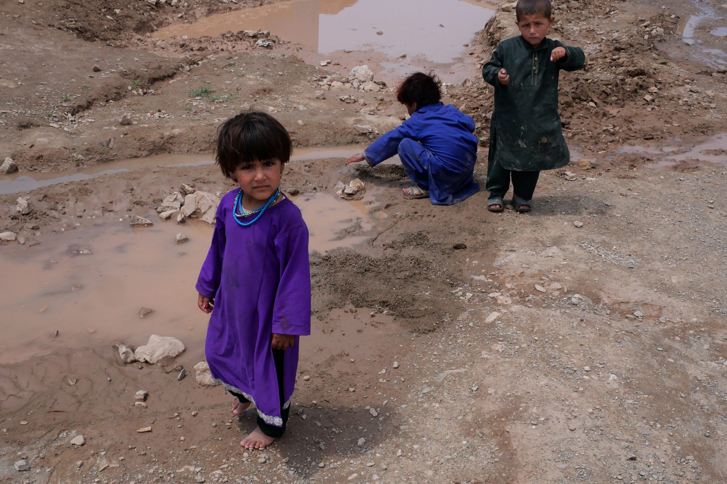 Afghan children play in the mud at an unofficial camp for internally displaced people in Herat, Afghanistan, May 2021. Photo: Charlie Faulkner