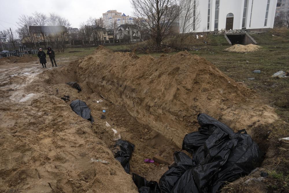 Neighbors gather next to the mass grave of civilians executed by Russian soldiers in Bucha, in the outskirts of Kyiv, Ukraine, on Sunday, 3 April 2022. Photo: Rodrigo Abd / AP Photo