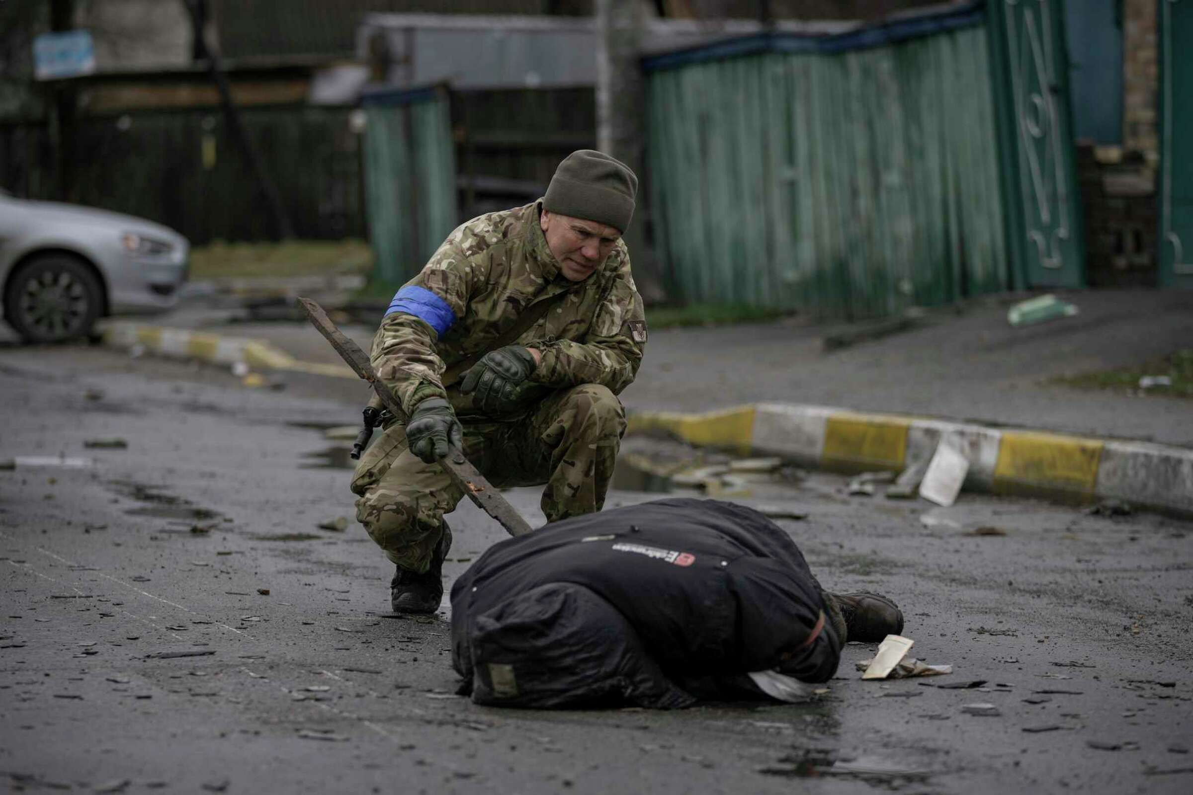 A Ukrainian serviceman uses a piece of wood to check if the body of a man dressed in civilian clothing is booby-trapped with explosive devices, in the formerly Russian-occupied Kyiv suburb of Bucha, Ukraine, on Saturday, 2 April 2022. As Russian forces pulled back from Ukraine's capital region, retreating troops created a "catastrophic" situation for civilians by leaving mines around homes, abandoned equipment and "even the bodies of those killed," Ukraine President Volodymyr Zelenskyy warned on Saturday. Photo: Vadim Ghirda / AP