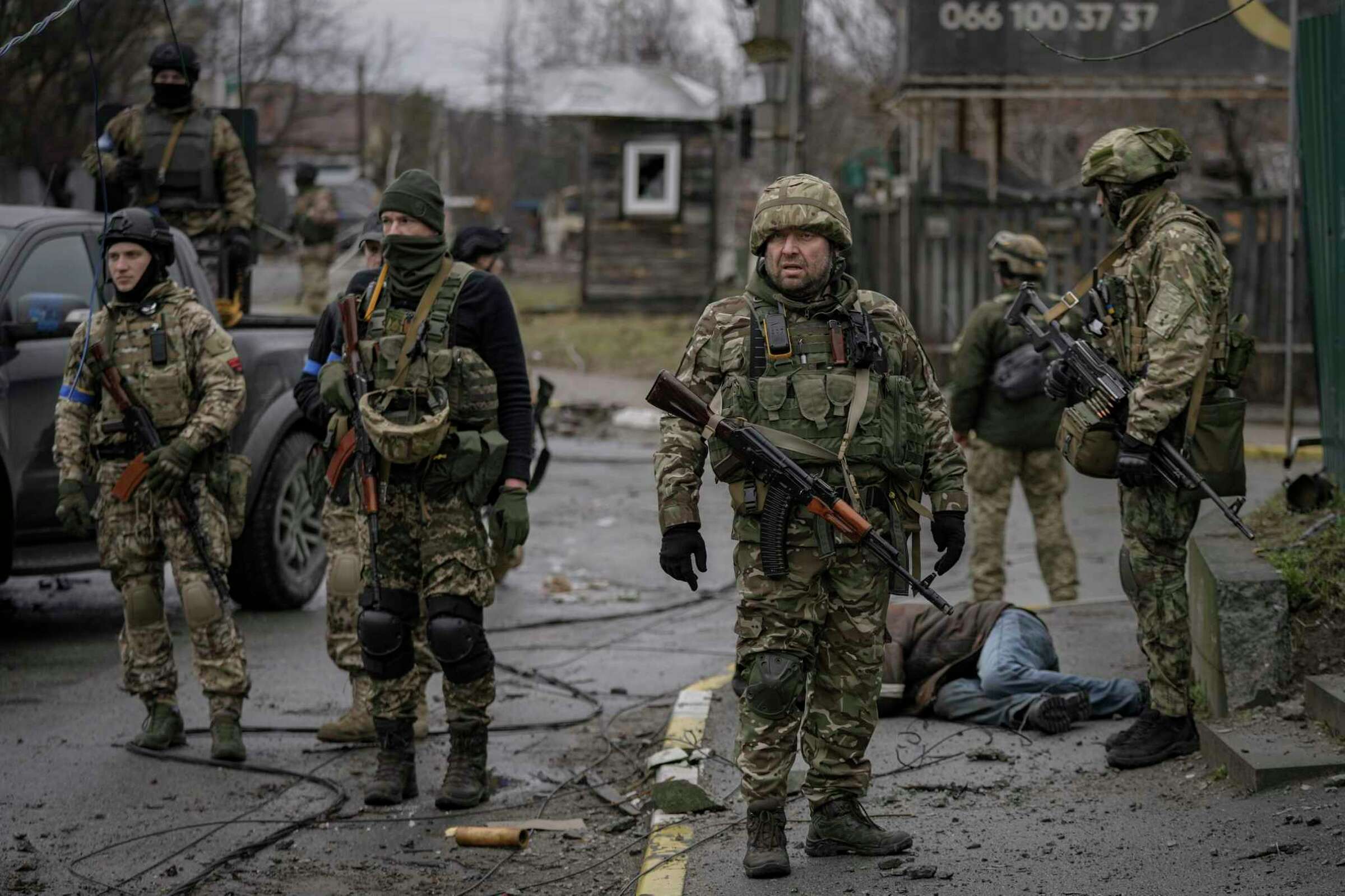 Ukrainian servicemen stand next to the body of man dressed in civilian clothing, in the formerly Russian-occupied Kyiv suburb of Bucha, Ukraine, on Saturday, 2 April 2022. Photo: Vadim Ghirda / AP