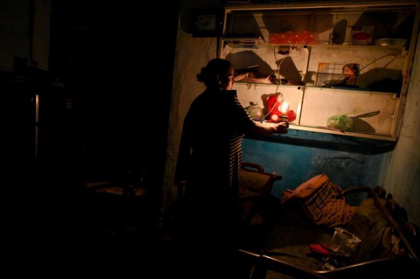 A woman uses a candle inside her house during a power cut in Colombo, Sri Lanka, on 30 March 2022. Many parts of the crisis-hit country faced up to 13 hours without electricity due to a shortage of foreign currency to import fuel. Photo: AFP