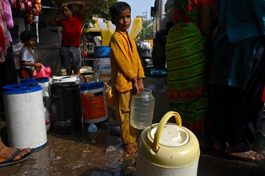 A boy stands in a queue to collect water for daily use from a water tanker provided by the municipal corporation at a slum on a hot summer day in New Delhi on 18 May 2022. Photo: Money Sharma / AFP / Getty Images