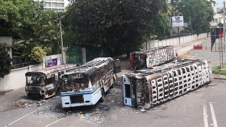 Burned buses near Sri Lanka’s former prime minister Mahinda Rajapaksa’s official residence, a day after they were torched by protesters in Colombo on 10 May 2022. The government imposed a three-day curfew following clashes between pro and anti-government demonstrators, amid the country’s economic crisis. Photo: Pradeep Dambarage / NurPhoto