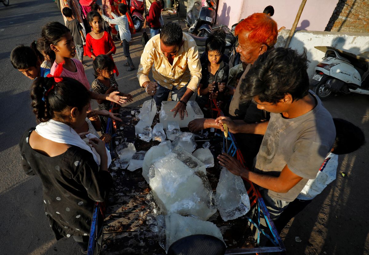 A man breaks a block of ice to distribute it among the residents of a slum during hot weather in Ahmedabad, India, 28 April 2022. Photo: Amit Dave / REUTERS