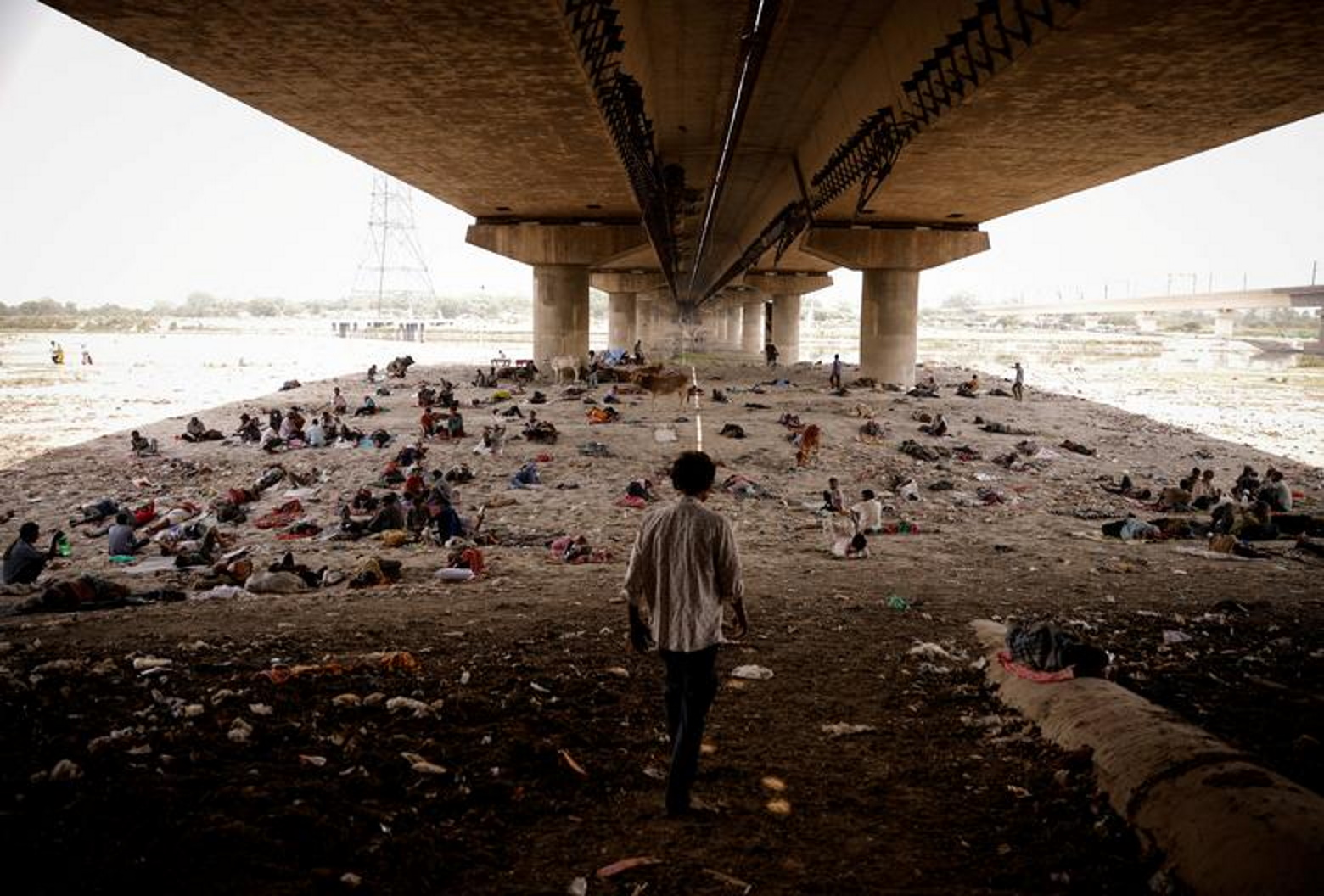 People sleep on the dried-up Yamuna riverbed under a bridge during a heatwave in New Delhi, India, 2 May 2022. Photo: Adnan Abidi / REUTERS
