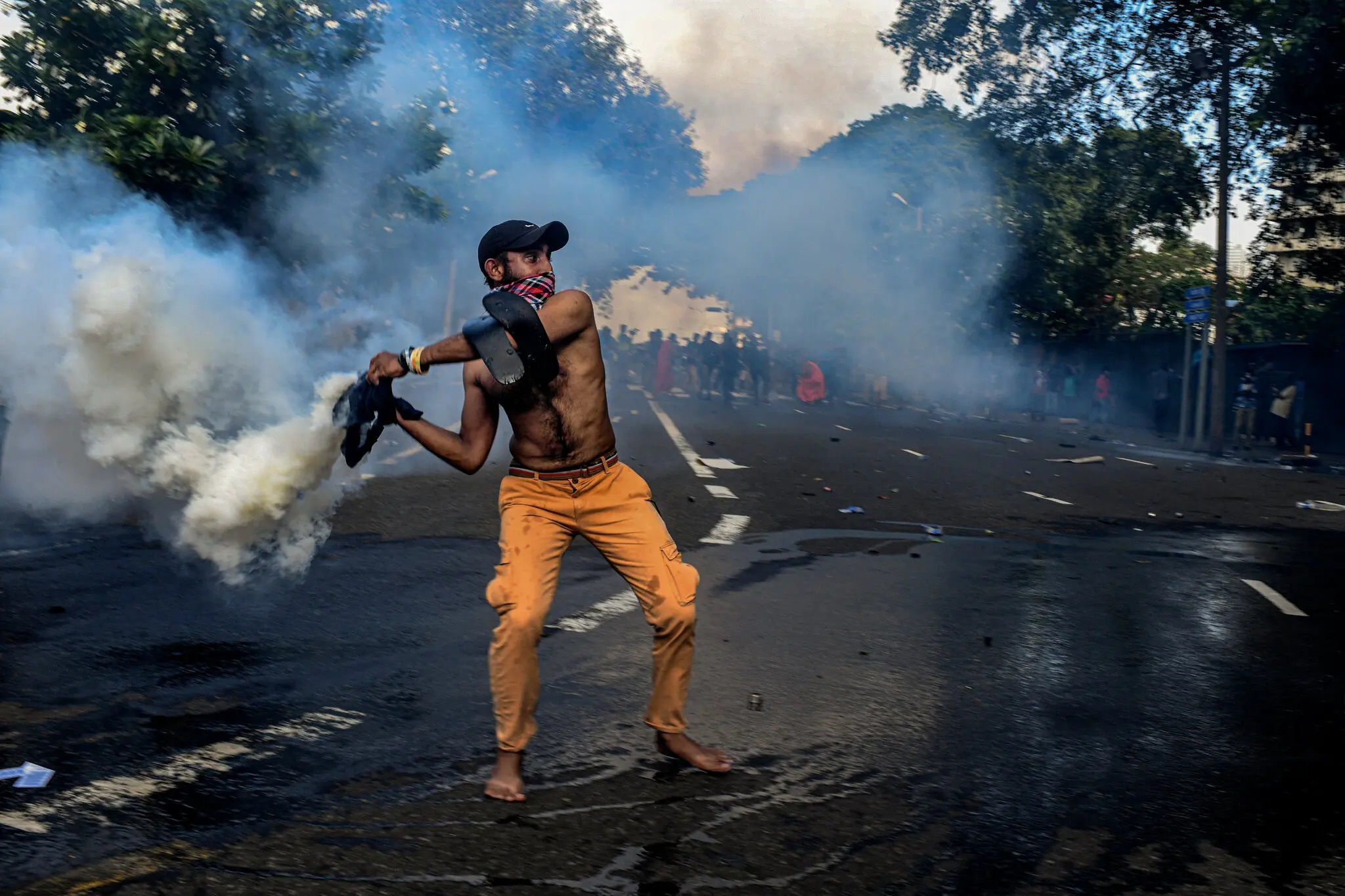 A protester in Sri Lanka hurls a tear-gas canister back at the police officers who fired it, 19 May 2022. Photo: Atul Loke / The New York Times