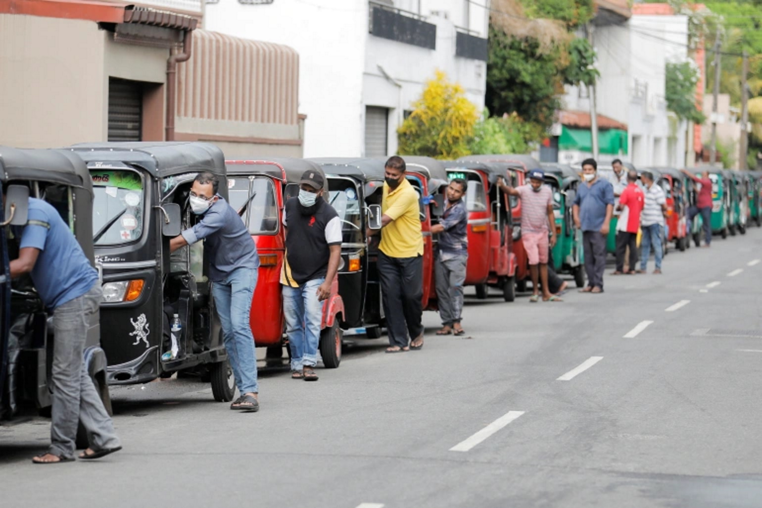 Drivers push their three-wheelers while waiting in line to buy petrol at a Ceypetco fuel station, amid the country's economic crisis, in Colombo, Sri Lanka, 12 April 2022. Photo: Dinuka Liyanawatte / REUTERS