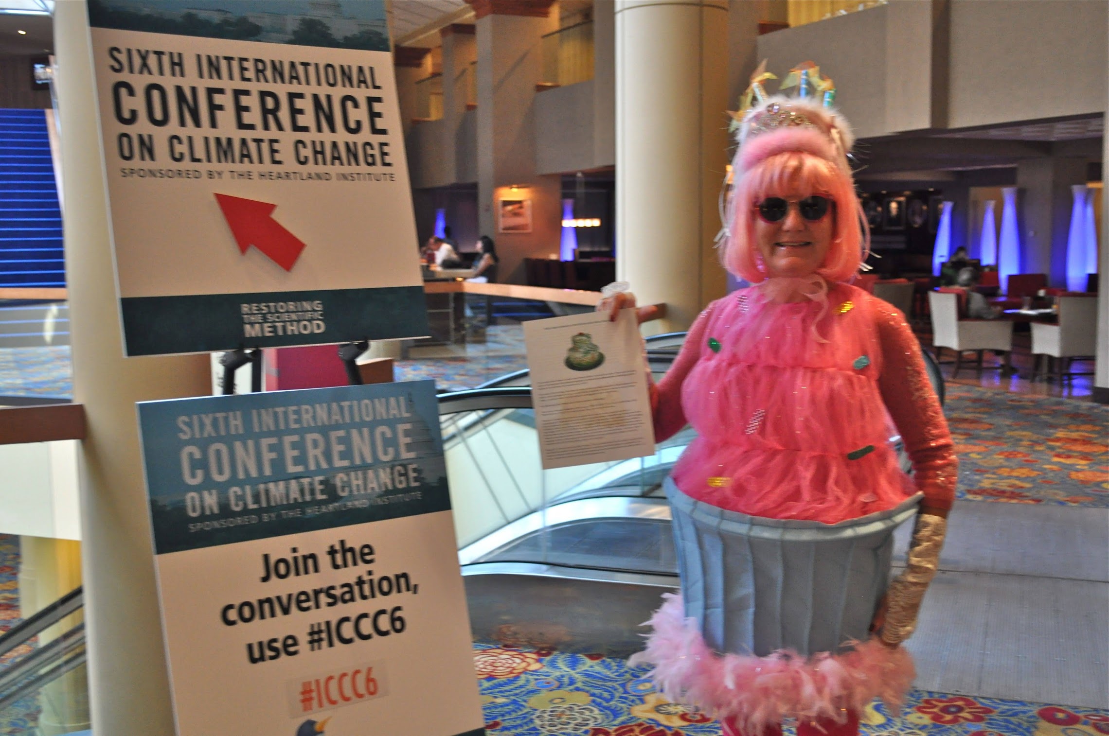 Gail Zawacki in cupcake costume protesting at the Heartland Institute’s sixth international climate denial conference, 30 June 2011. She designed the cupcake costume “to demonstrate in a non-threatening, cheerful image the simple verity that ‘climate change is baked in the cake’”. Photo: Gail Zawacki / Wit’s End