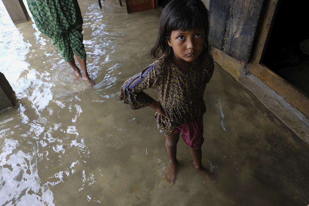 A girl reacts to the camera as her family members inspect their damaged belongings at her home, while flood water levels recede slowly in Sylhet, Bangladesh, Wednesday, 22 June 2022. Photo: Mahmud Hossain Opu / AP Photo