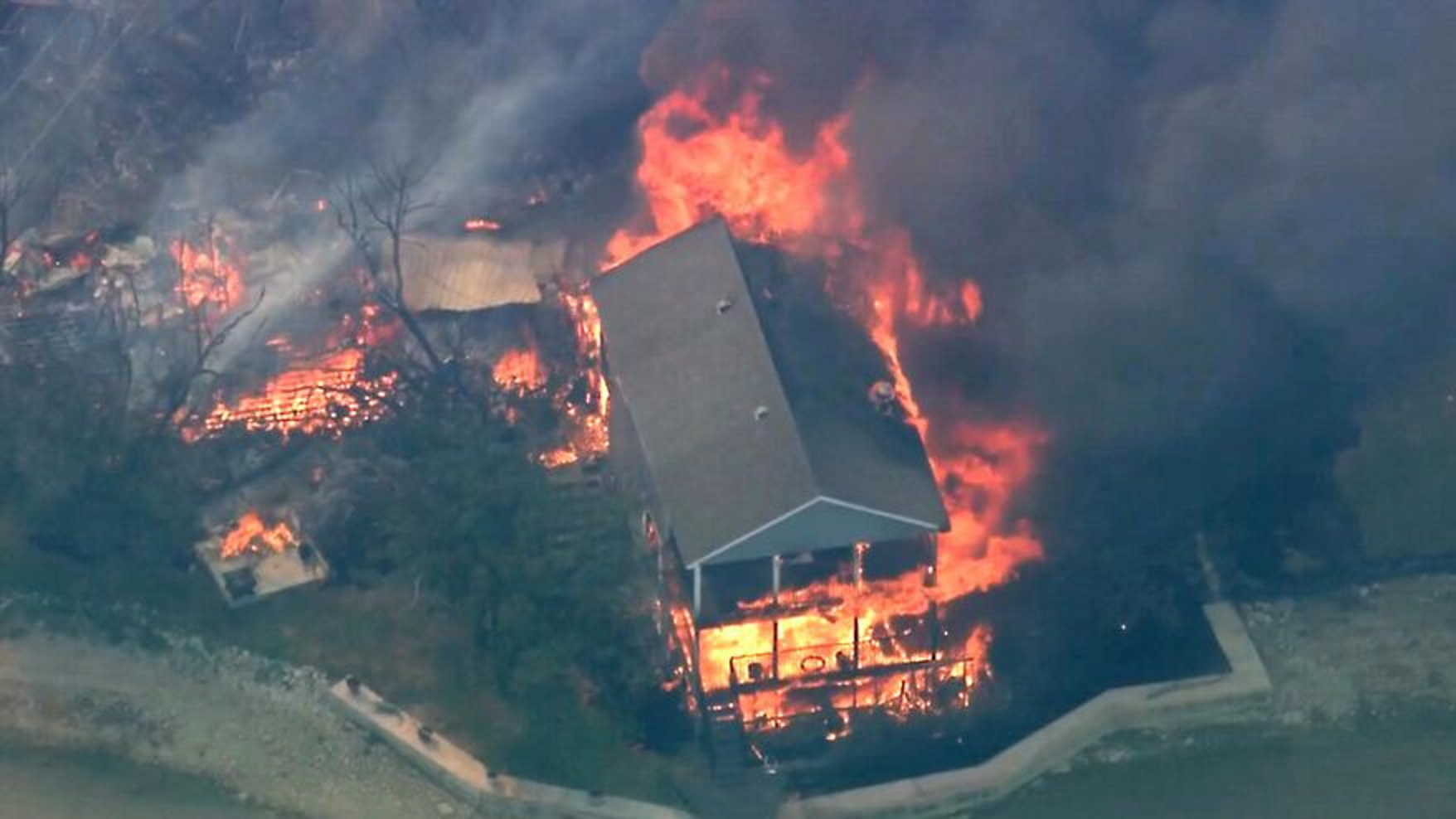 Aerial view of a structure burning during a wildfire in Palo Pinto County, Texas on Monday, 18 July 2022. The 110-degree heat wave caused a record 24 wildfires in Texas this week. Two Texas wildfires consumed at least 21 homes amid the record heat wave. Photo: KDFW FOX 4 / AP