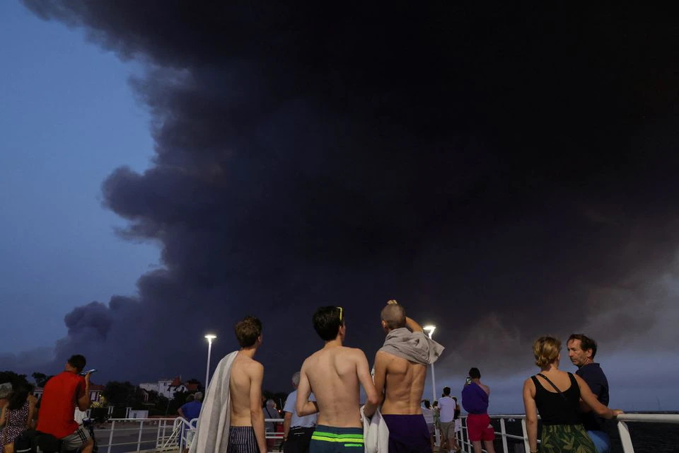 Beachgoers watch smoke produced by wildfires in La Teste-de-Buch forest, Arcachon, France, 18 July 2022. Photo: Pascal Rossignol / REUTERS