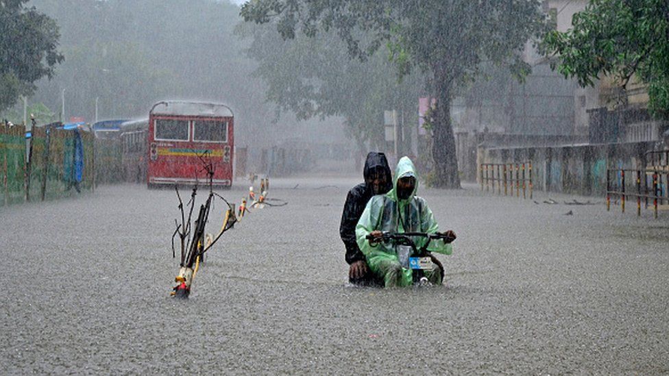 A delivery boy with an electric cycle wades through a flooded street due to heavy rainfall in Mumbai, India, 5 July 2022. Photo: Getty Images