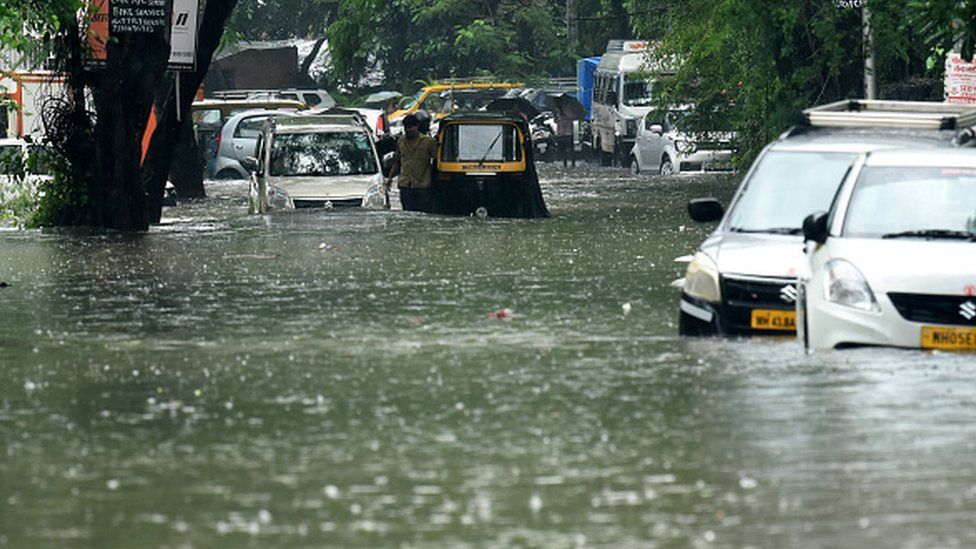 Vehicles drive through a flooded street during rain showers in Mumbai on 5 July 2022. Photo: Getty Images