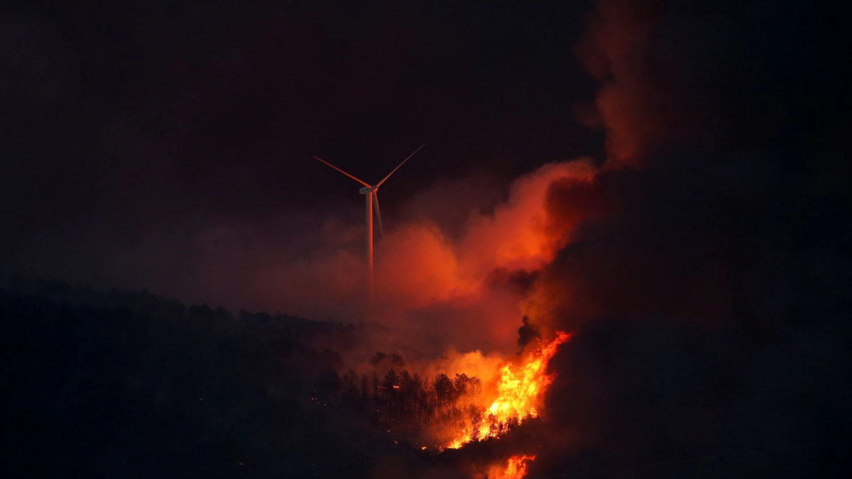 A wildfire burns near a wind turbine at night outside Tabara, Zamora, during the second heatwave of the year in Spain, 18 July 2022. Photo: Isabel Infantes / REUTERS