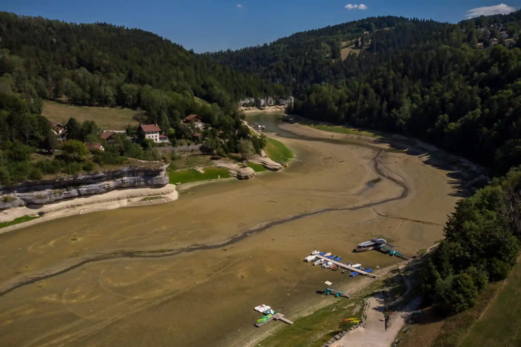 An aerial view taken on 4 August 2022 shows the dry bed of Lac des Brenets, part of the Doubs River – a natural border between eastern France and western Switzerland. As much of Europe baked in its third heatwave since June 2022, the river has dried up. This is due to a combination of factors, including geological faults that drain the river, decreased rainfall, and heatwaves. Photo: Fabrice Coffrini / AFP / Getty Images