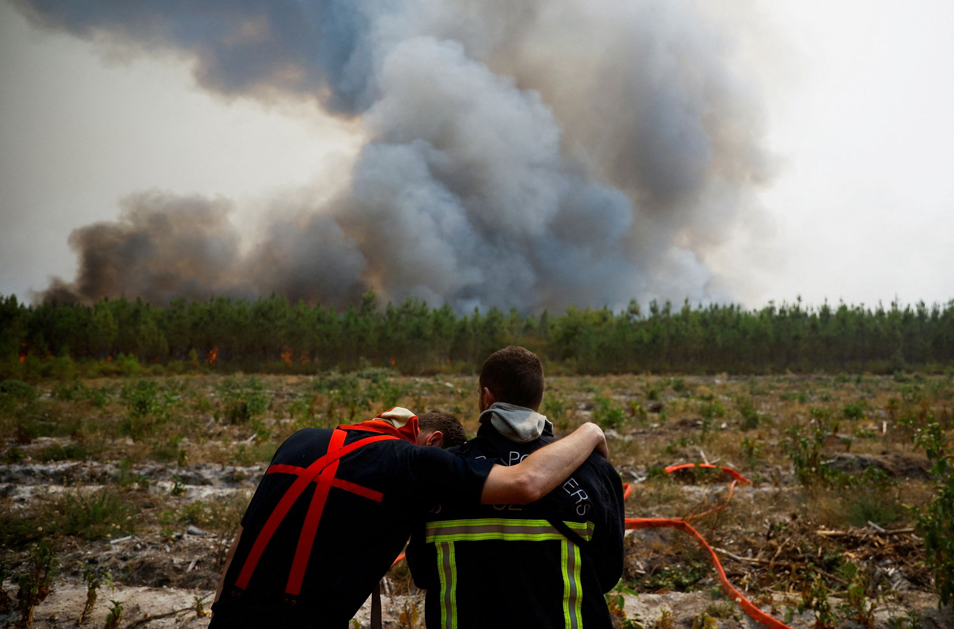 Firefighters embrace as they work to contain a fire in Saint-Magne, as wildfires continue to spread in the Gironde region of southwestern France, 11 August 2022. Stephane Mahe / REUTERS