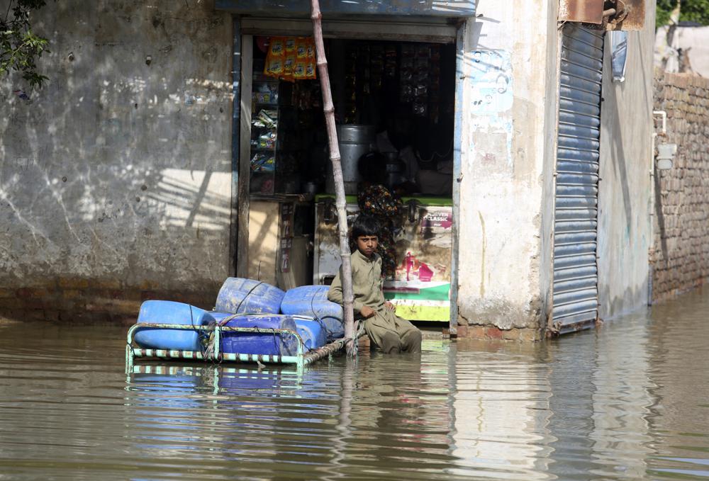 A child victim of unprecedented flooding from monsoon rains sits in front a shop in Jaffarabad, Pakistan, Monday, 5 September 2022. Photo: Fareed Khan / AP Photo