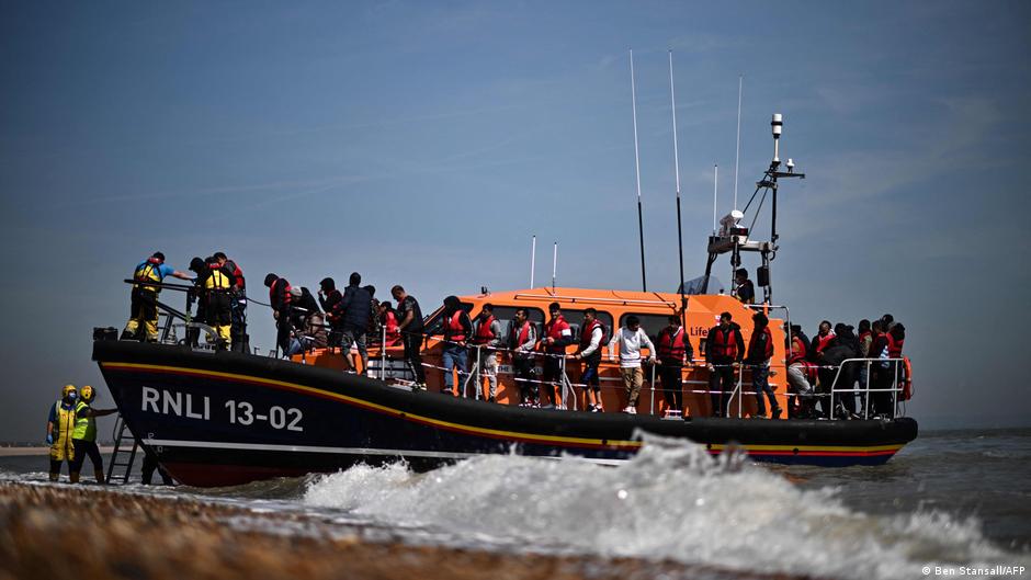 A British police officer stands guard on the beach of Dungeness, England, on 15 June 2022, as Royal National Lifeboat Institution's (RNLI) staff help migrants disembark from one of their lifeboats. Photo: Ben Stansall / AFP / Getty Images