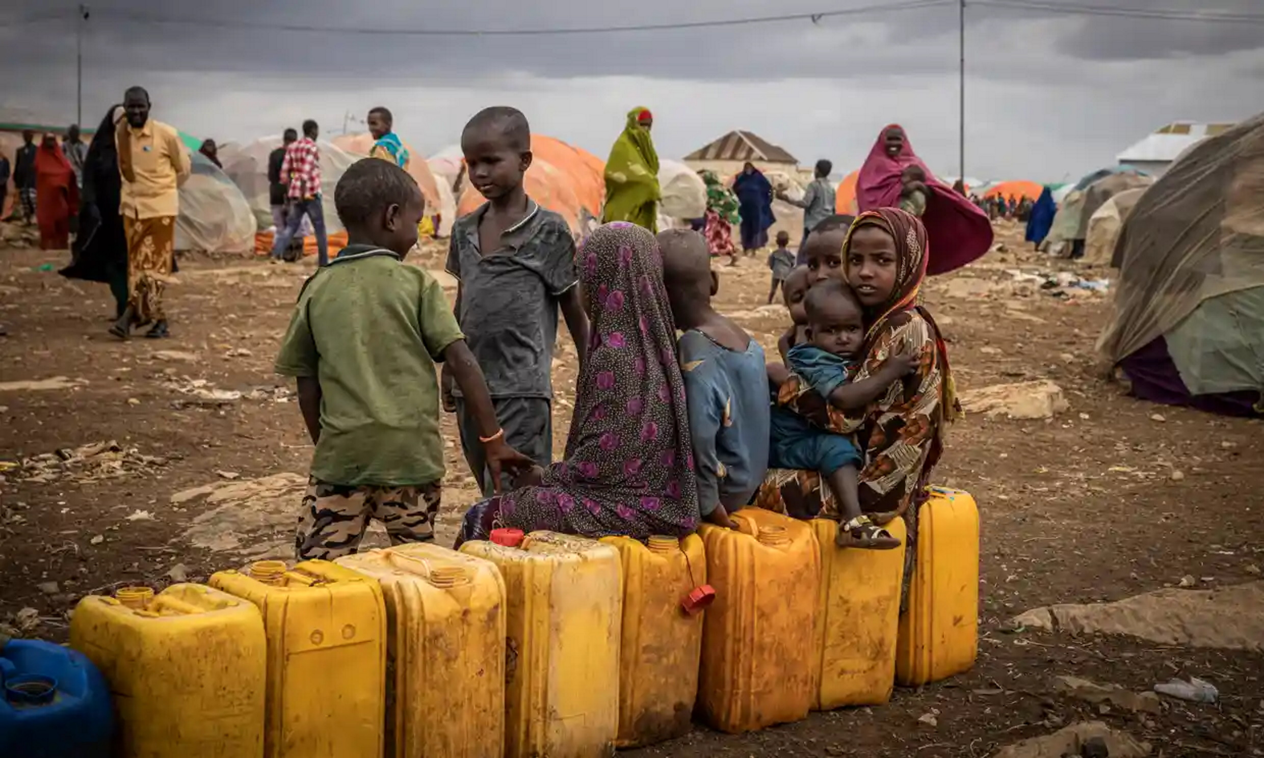 Children sit on water bottles waiting to be filled among tents in a displacement camp for people hit by drought in Baidoa, Somalia. Photo: Ed Ram / Getty