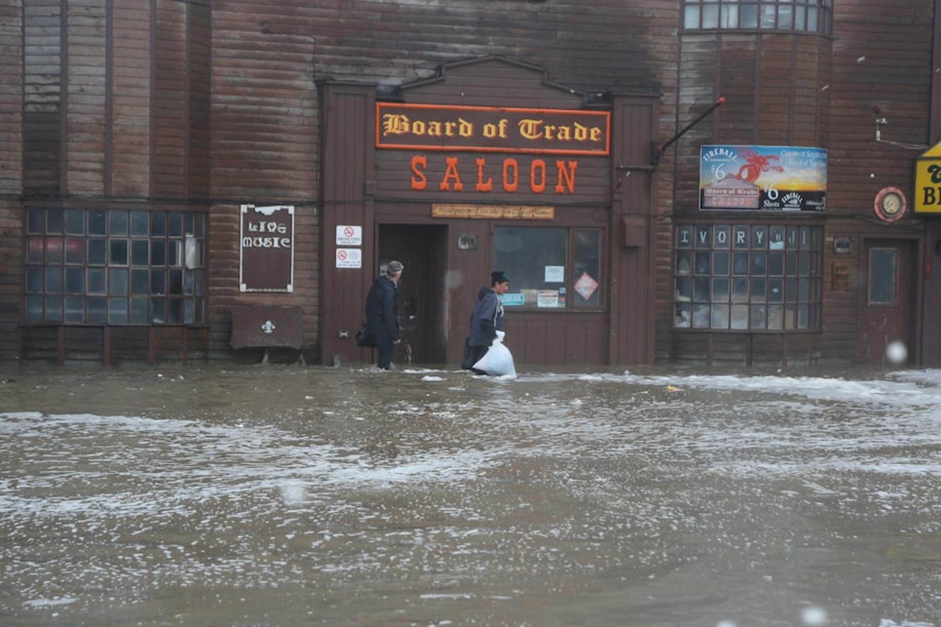 Two men walk through rushing water on Front Street in Nome, Alaska, just a half block from the Bering Sea, on 17 September 2022. Photo: Peggy Fagerstrom / AP