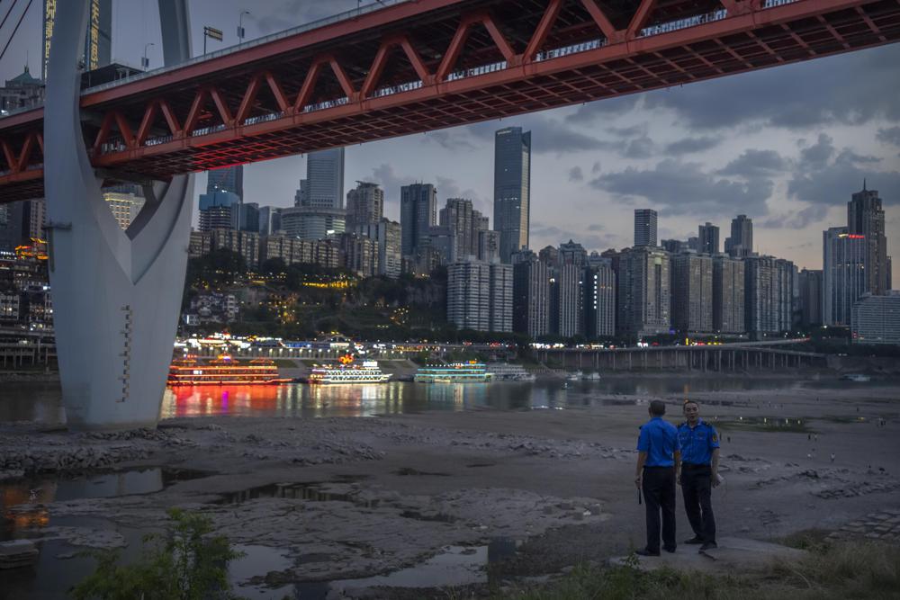 Security officers stand on a hillside after clearing away visitors from the dry riverbed of the Jialing River, a tributary of the Yangtze, in southwestern China's Chongqing Municipality, 20 August 2022. Widespread drought that dried up large parts of Europe, the United States and China this past summer was made 20 times more likely by climate change, according to a new study. Photo: Mark Schiefelbein / AP Photo