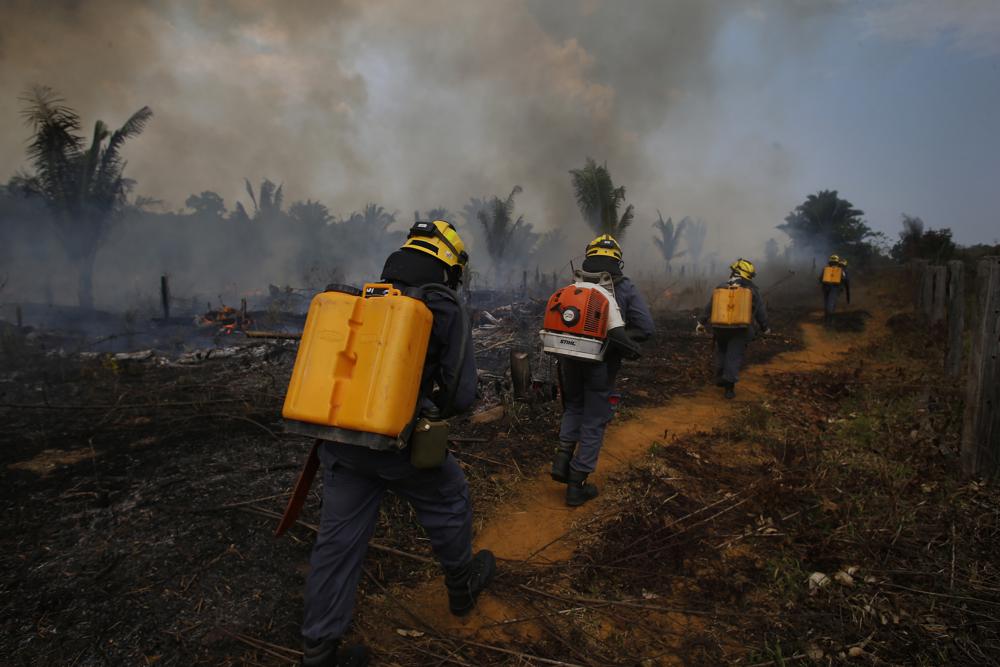 Fire brigade members walk in to a burnt area in Apui, Amazonas state, Brazil, 21 September 2022. Despite the smoke clogging the air of entire Amazon cities, state elections have largely ignored environmental issues. Far-right President Jair Bolsonaro is seeking a second four-year term against leftist Luiz Inácio Lula da Silva, who ruled Brazil between 2003 and 2010. Photo: Edmar Barros / AP Photo