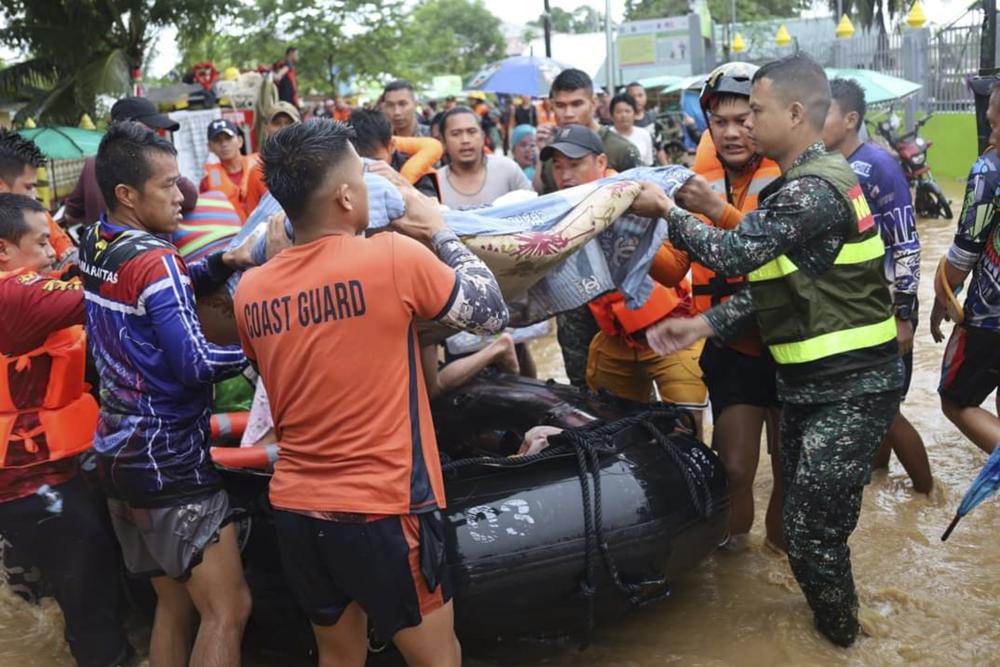 In this photo provided by the Philippine Coast Guard, rescuers carry a resident to safer grounds as floods rose due to Tropical Storm Nalgae at Parang, Maguindanao province, southern Philippines on Friday, 28 October 2022. Photo: Philippine Coast Guard / AP News