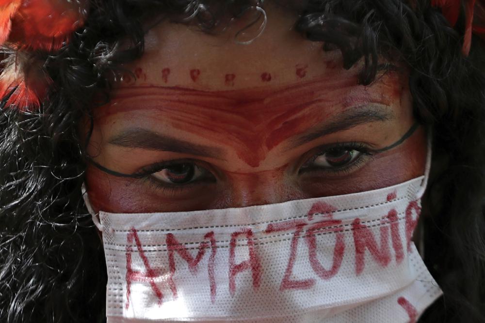 An Indigenous woman wears a protective face mask as a precaution against COVID-19 during a protest against Brazilian President Jair Bolsonaro's proposals to allow mining on Indigenous lands, at the Esplanade of Ministries in Brasilia, Brazil, 20 April 2021. Bolsonaro’s administration introduced legislation that would open up Indigenous territories to mining — something federal prosecutors have called unconstitutional, and activists warn would wreak vast social and environmental damages. Photo: Eraldo Peres / AP Photo