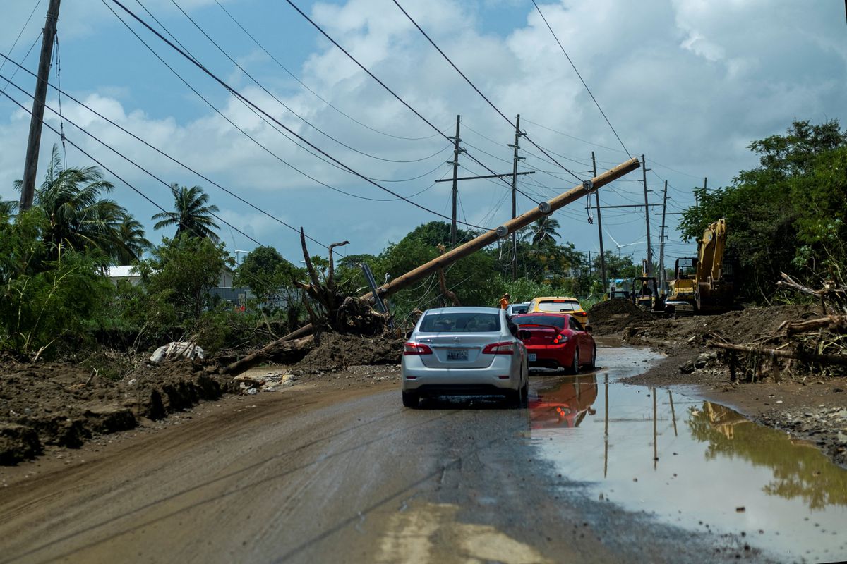 Cars drive under a downed power pole in the aftermath of Hurricane Fiona in Santa Isabel, Puerto Rico, 21 September 2022. Photo: Ricardo Arduengo / REUTERS