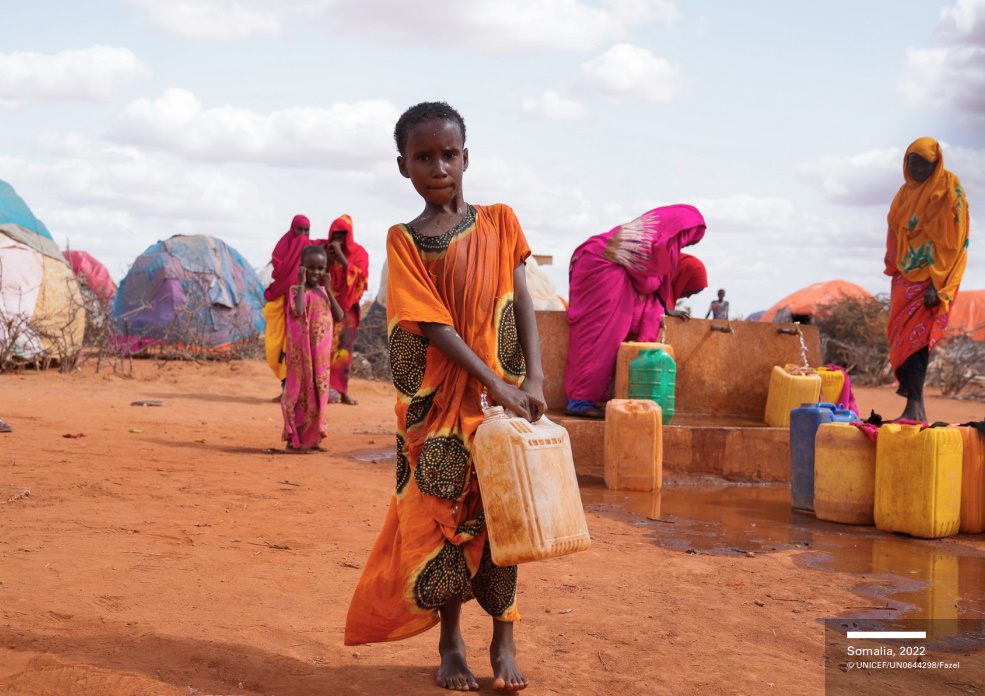 A child in a refugee camp carries water in Somalia, 2022. Somalia faces widespread famine after four failed rainy seasons, with a fifth season underway that likely will fail too, along with the sixth early in 2023. Photo: Fazel / UNICEF