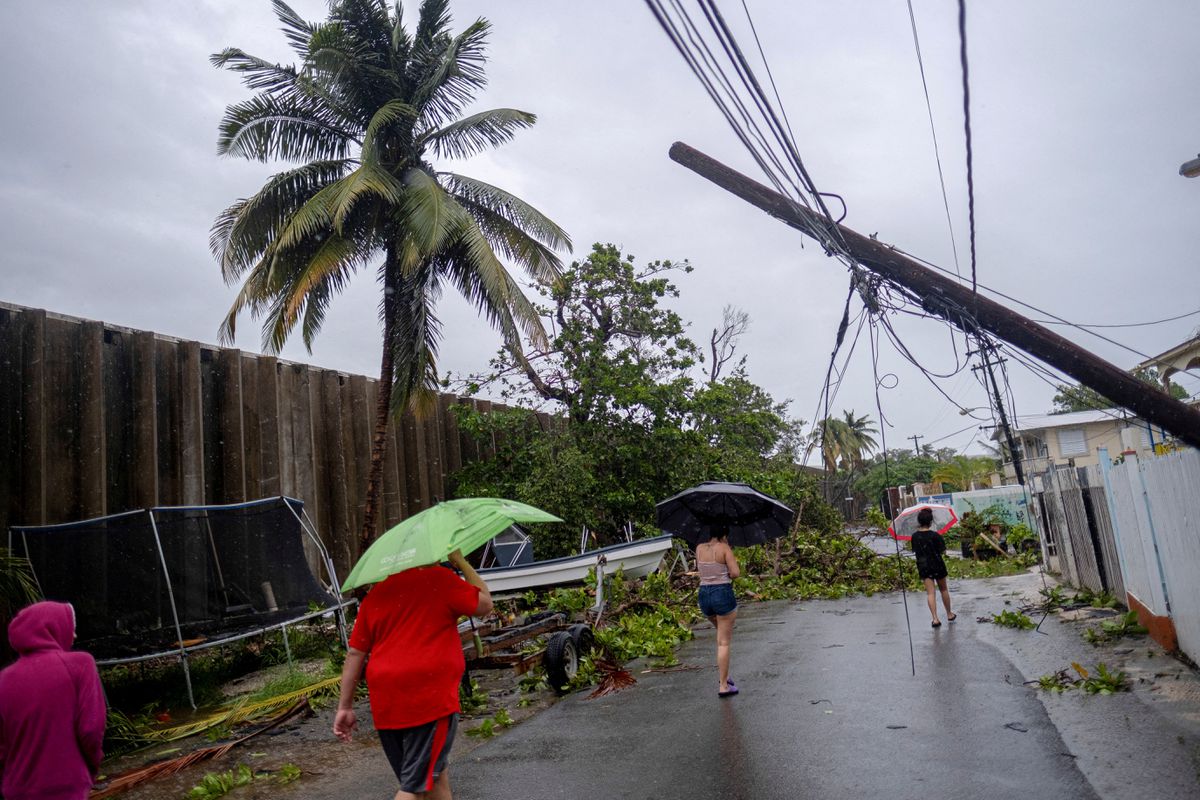 People walk on a street affected by the passing of Hurricane Fiona in Penuelas, Puerto Rico, 19 September 2022. Ricardo Arduengo / REUTERS